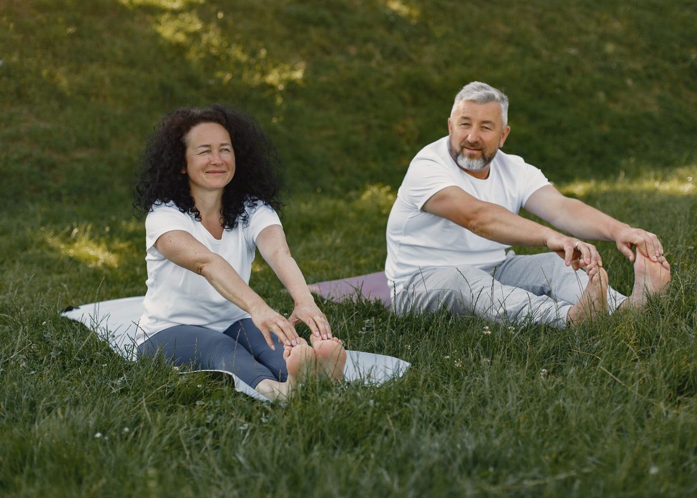 Older couple stretching outdoors on grass